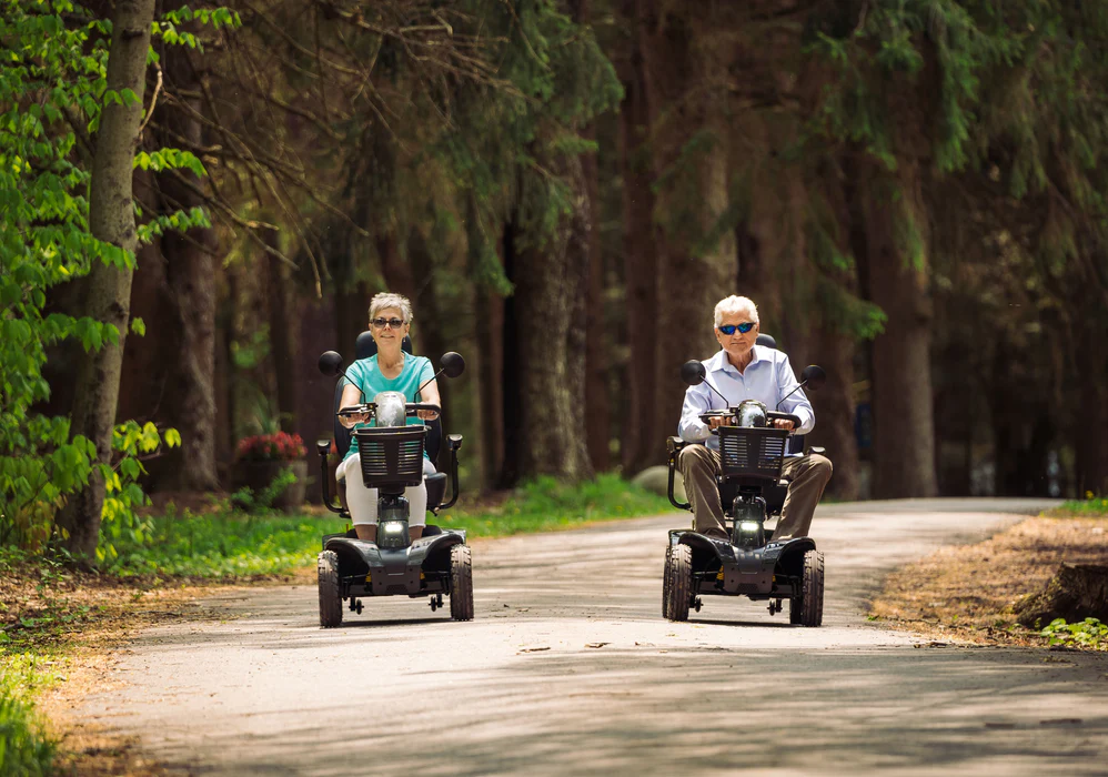 Mobility scooter repair Ireland — couple enjoying their mobility scooters on a forest path